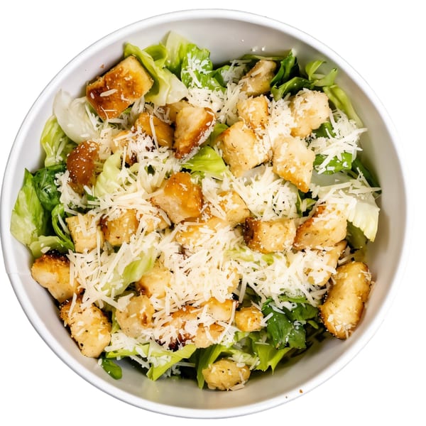 A white bowl filled with a Caesar salad, featuring crisp lettuce, golden croutons, and shredded Parmesan cheese.
